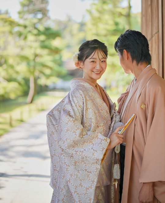 白い花模様を一面に散りばめた可憐な色打掛。細やかな意匠が織りなす優美な世界観に、動くたびきらりと覗くゴールドの裏地が花嫁心をそっとくすぐる。華やかさと上品さを兼ね備え、晴れの日をより格別に彩る特別な一着。（花華金白／衣装番号DMOS16）