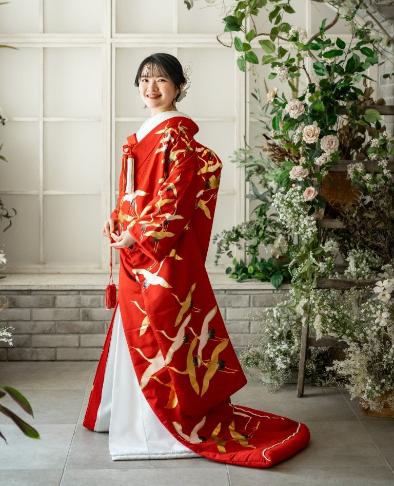 赤地に金と白の鶴が舞う色打掛をまとった花嫁。白いアーチ窓と生花に囲まれた横浜のスタジオで撮影した和装前撮り（鶴黄／衣装番号YB13）