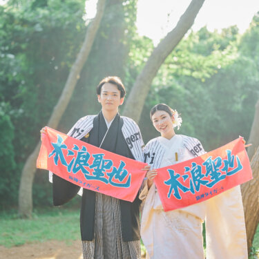 ユニフォームを羽織り、応援タオルを広げて笑う紋付袴の新郎と白無垢の花嫁。野球好きのふたりらしい和装前撮りのアイテム