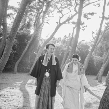 城ヶ島の松林の小道を笑い合いながら歩く紋付袴の新郎と白無垢の花嫁。モノクロで仕上げた和装の結婚写真