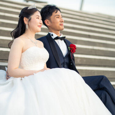ウッドデッキの階段に寄り添って座り、同じ方向を見つめるティアラの花嫁と新郎の洋装前撮り