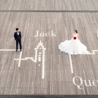 横浜三塔の絵と'Jack''Queen'の文字が描かれた大さん橋のデッキに立つ新郎新婦を真上から写した遊び心ある前撮り
