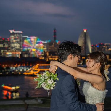 ライトアップされた観覧車とビル群を背に抱き合う新郎新婦。横浜みなとみらいの夜景が輝くナイトフォトのフォトウェディング