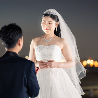夜の港で新郎から指輪を受け取り、ベールとティアラ姿で微笑む花嫁のプロポーズシーンの前撮り