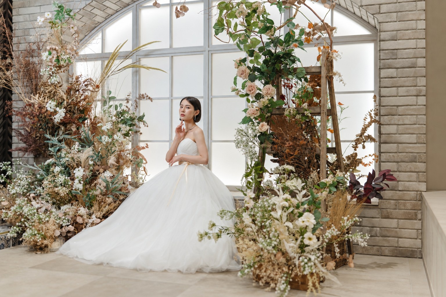 ドライフラワーとレンガのアーチ窓を背に佇むベアトップのウェディングドレスの花嫁。横浜リゾートスタジオの洋装＆和装スタジオフォト